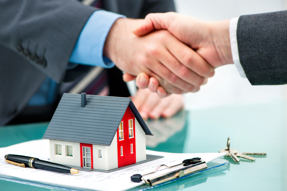 Fastighetsmäklare skakar hand med kund efter kontrakt signatur